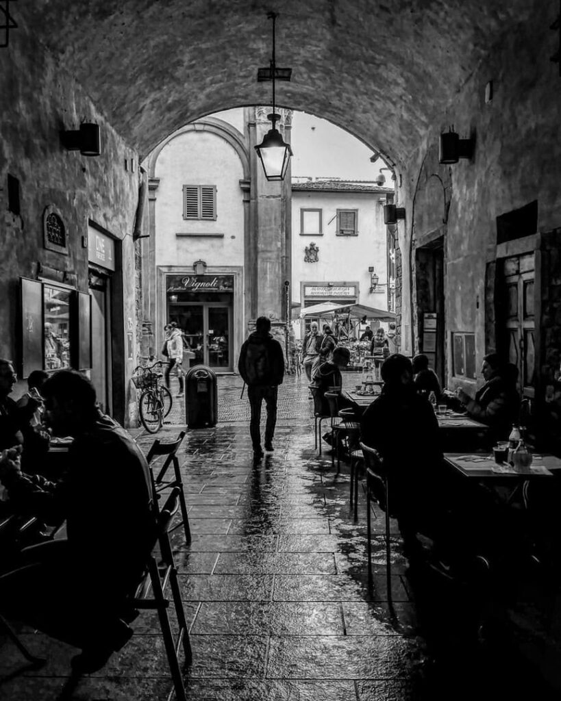 persone sedute locali sotto l'arco di San pierino Firenze foto in bianco e nero